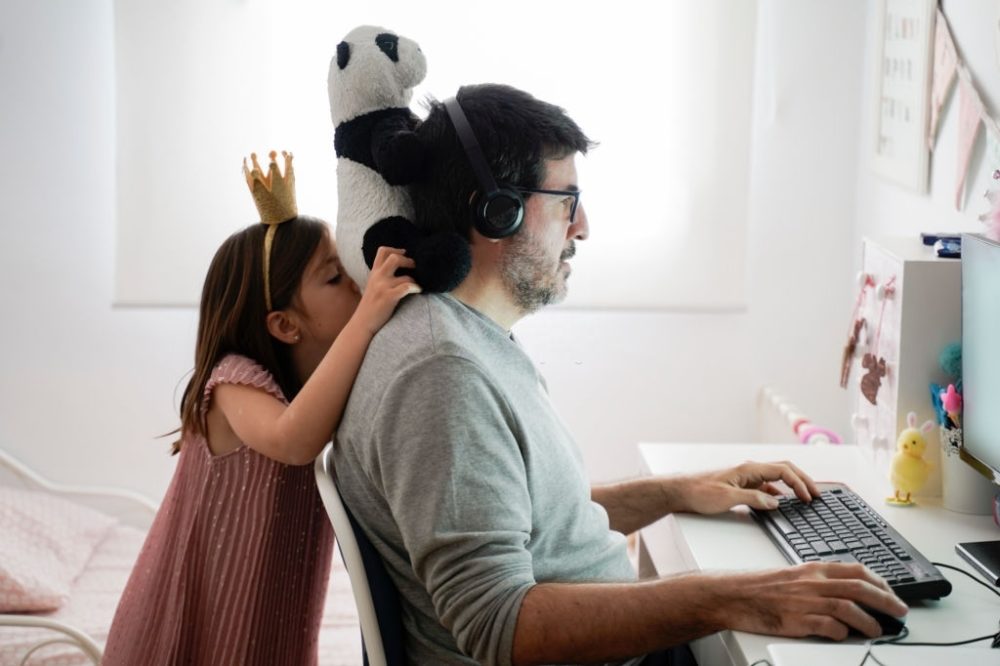 man remote working with his daughter