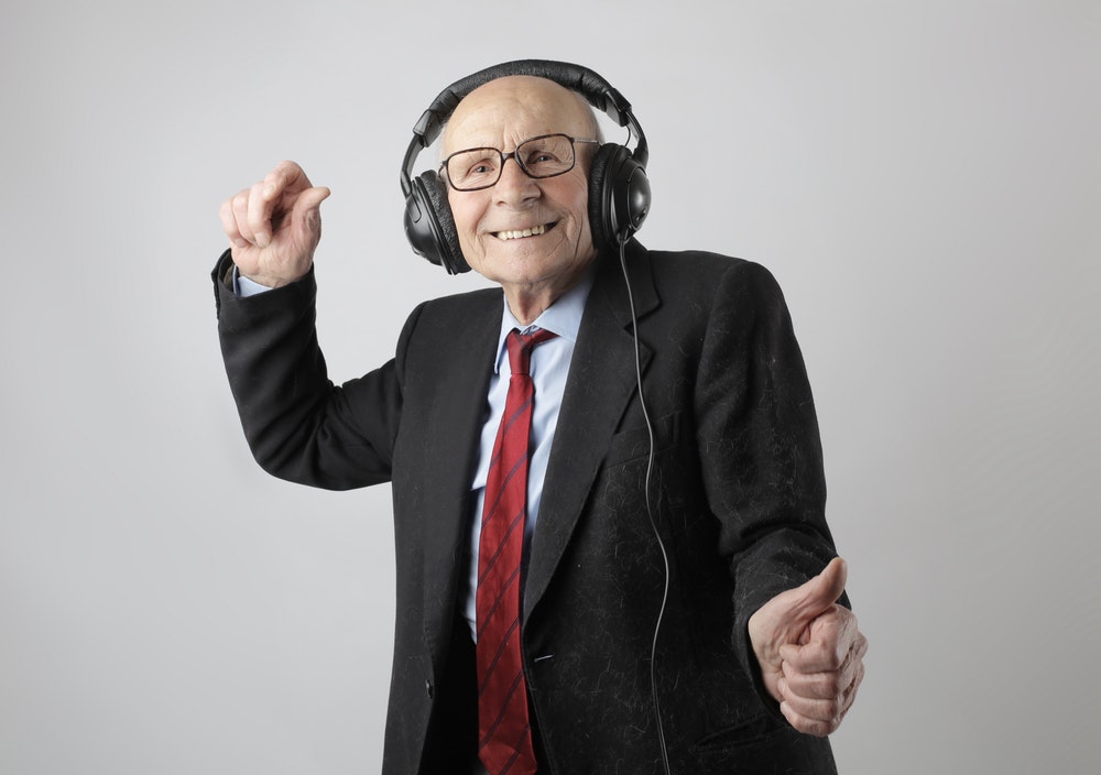 Old man in a suit dancing and listening to music