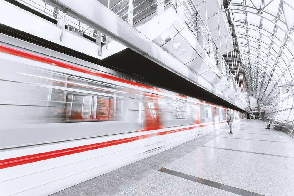 High speed train passing a passenger on a platform.