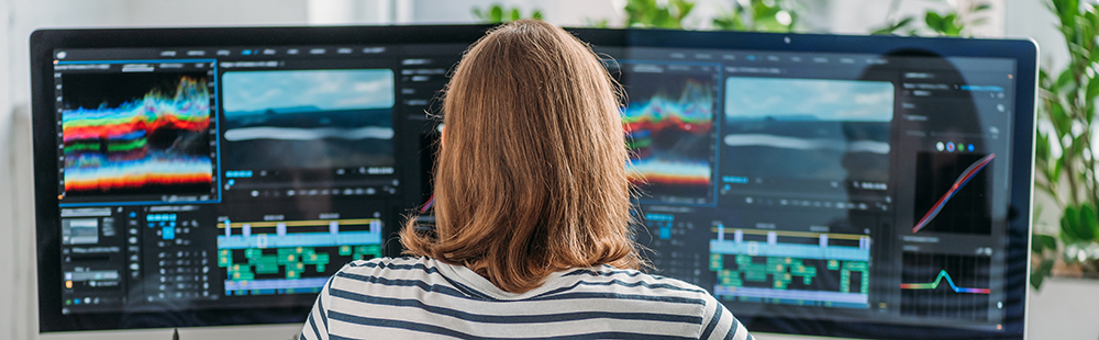 panoramic shot of editor working near two computer monitors