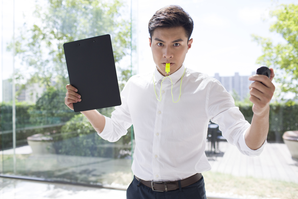 Young Asian businessman blowing whistle