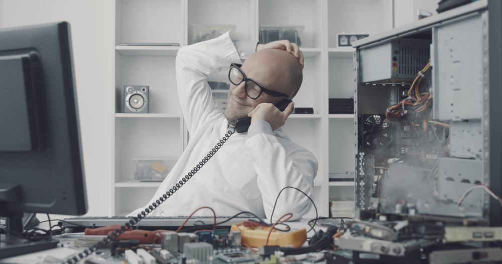 Distracted computer repair technician having a phone call while the computer is short-circuiting