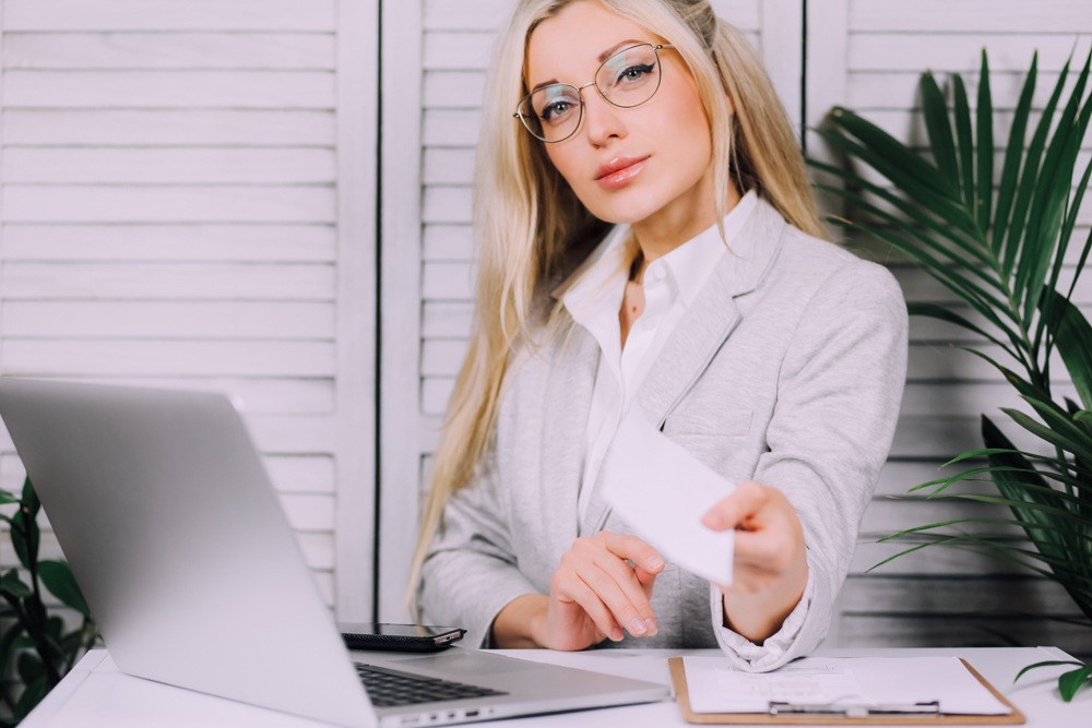 Do you know how to avoid a payroll diversion attack? Young woman handing over a payroll check. 