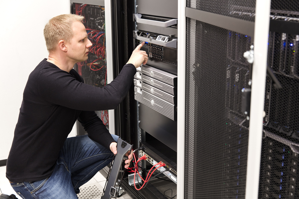 It engineer or consultant work with server in data rack. Shot in large datacenter.