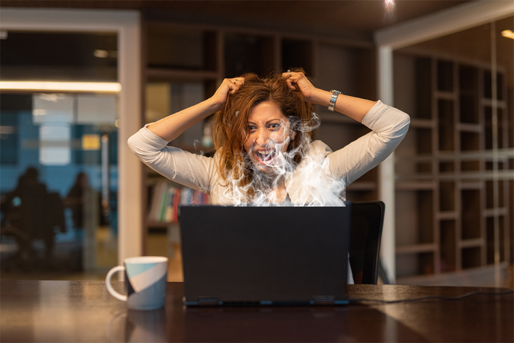 Angry and frustrated woman using laptop computer in office horizontal shot