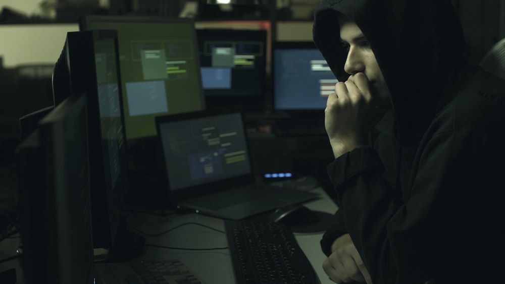 Young professional hacker working in a dark office with computers, cyber security and hacking concept