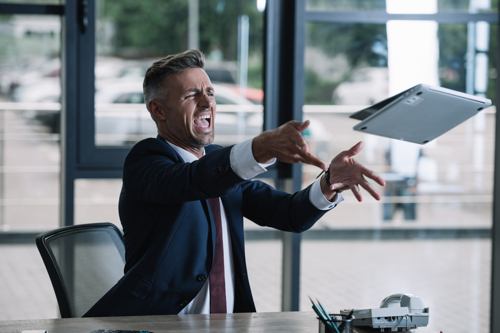 angry businessman throwing a laptop in office because he doesn't know how to use it