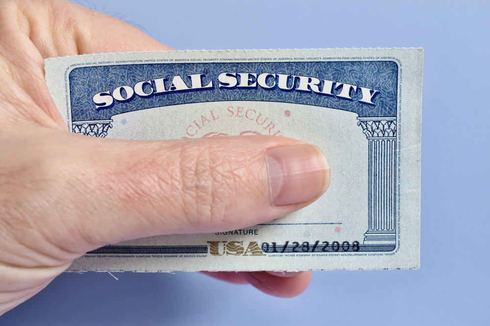 A person holding a social security card covering the numbers with their thumb