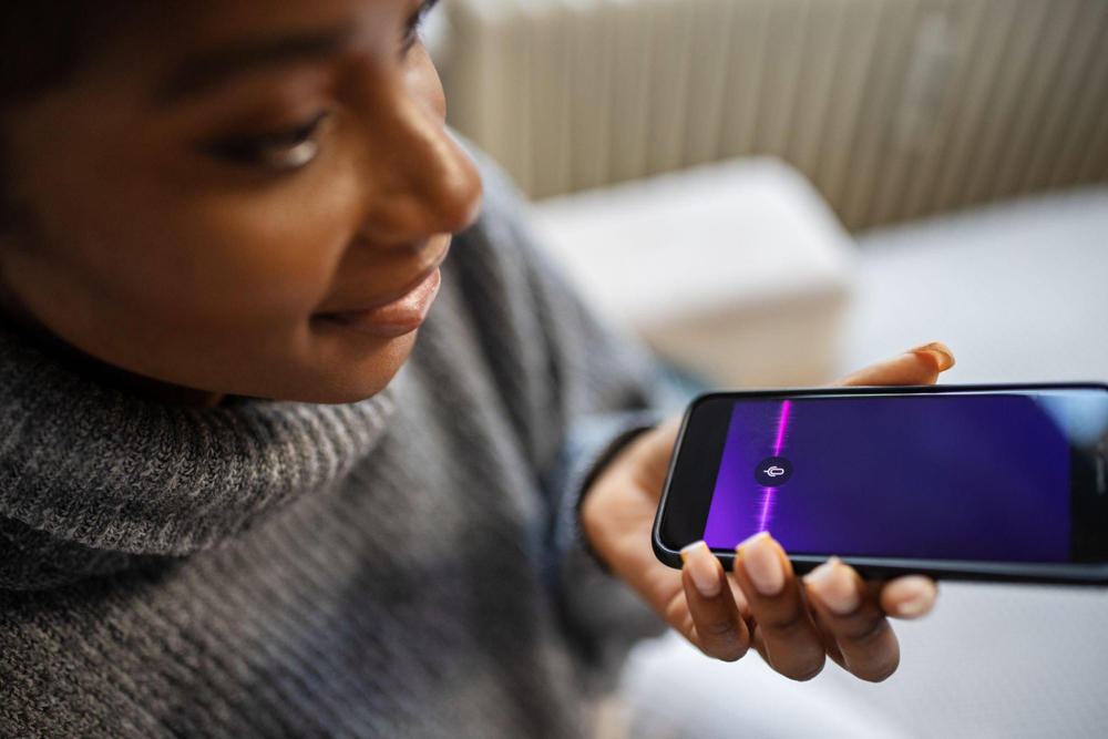 Woman recording her voice on a smartphone that might be used for voice cloning.