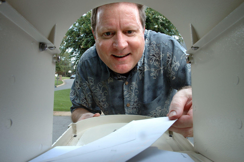 Man looking inside his mailbox with a confused expression