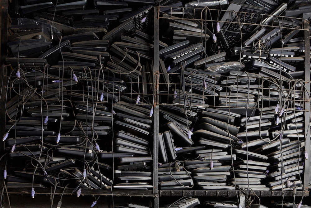 A pile of old keyboards and laptops stacked to the ceiling